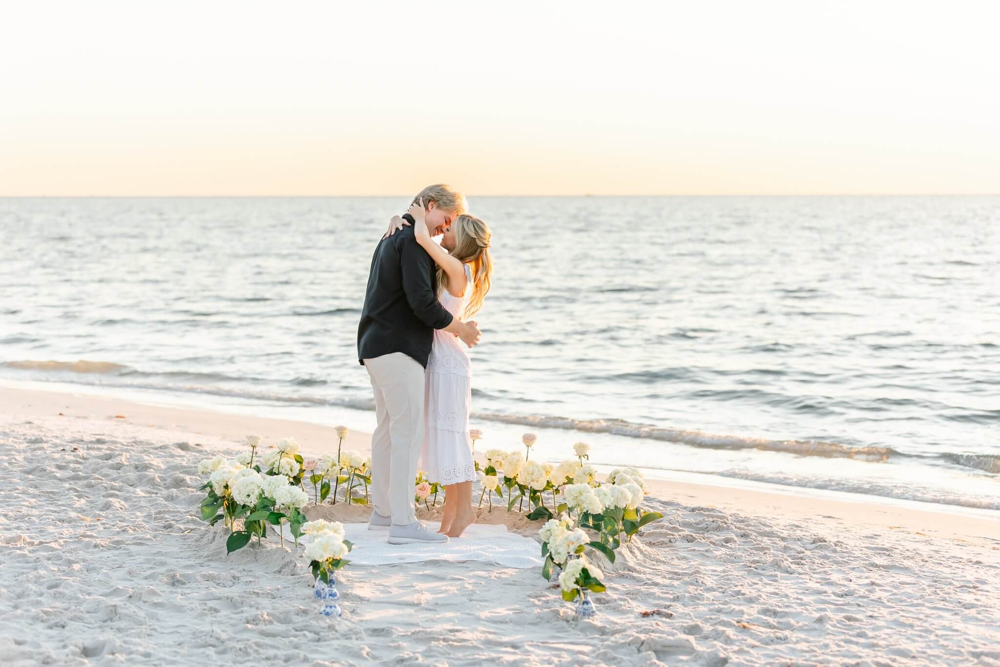 couple kissing surrounded by flowers on the beach by one of the top naples photographers