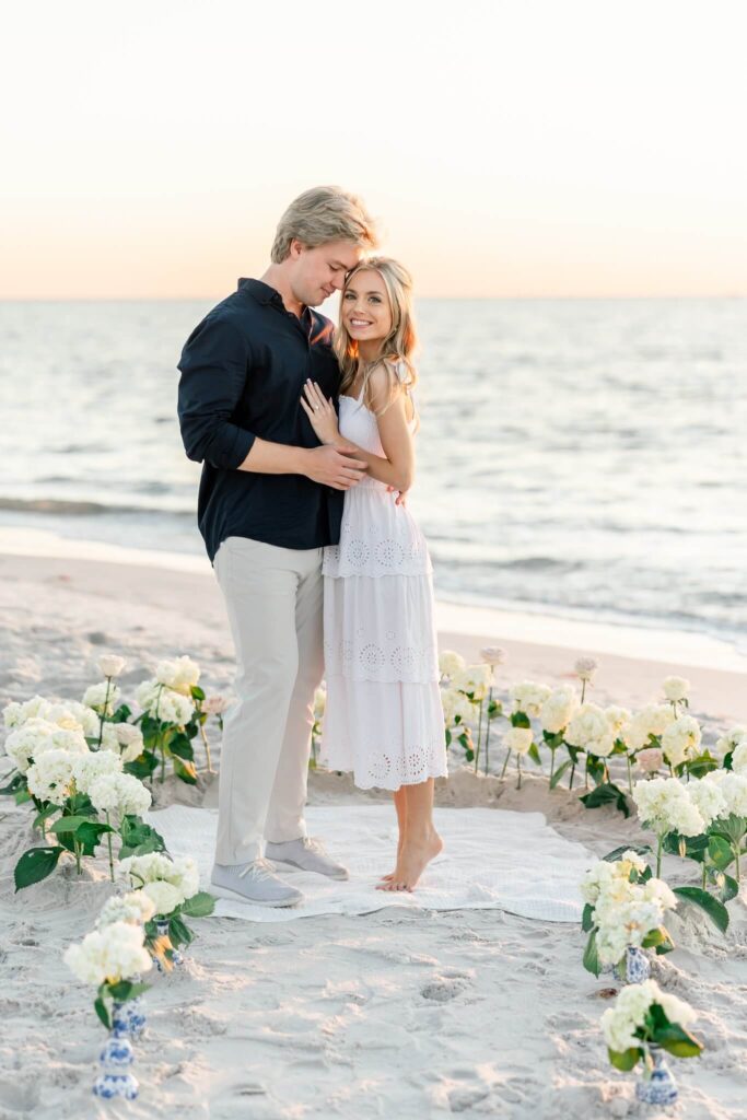 couple embracing on beach at proposal by naples photographers